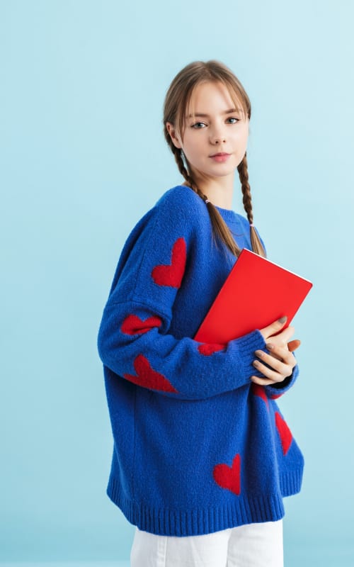 young-pretty-girl-with-braids-in-oversize-printed-sweater-holding-notebook-dreamily.jpg